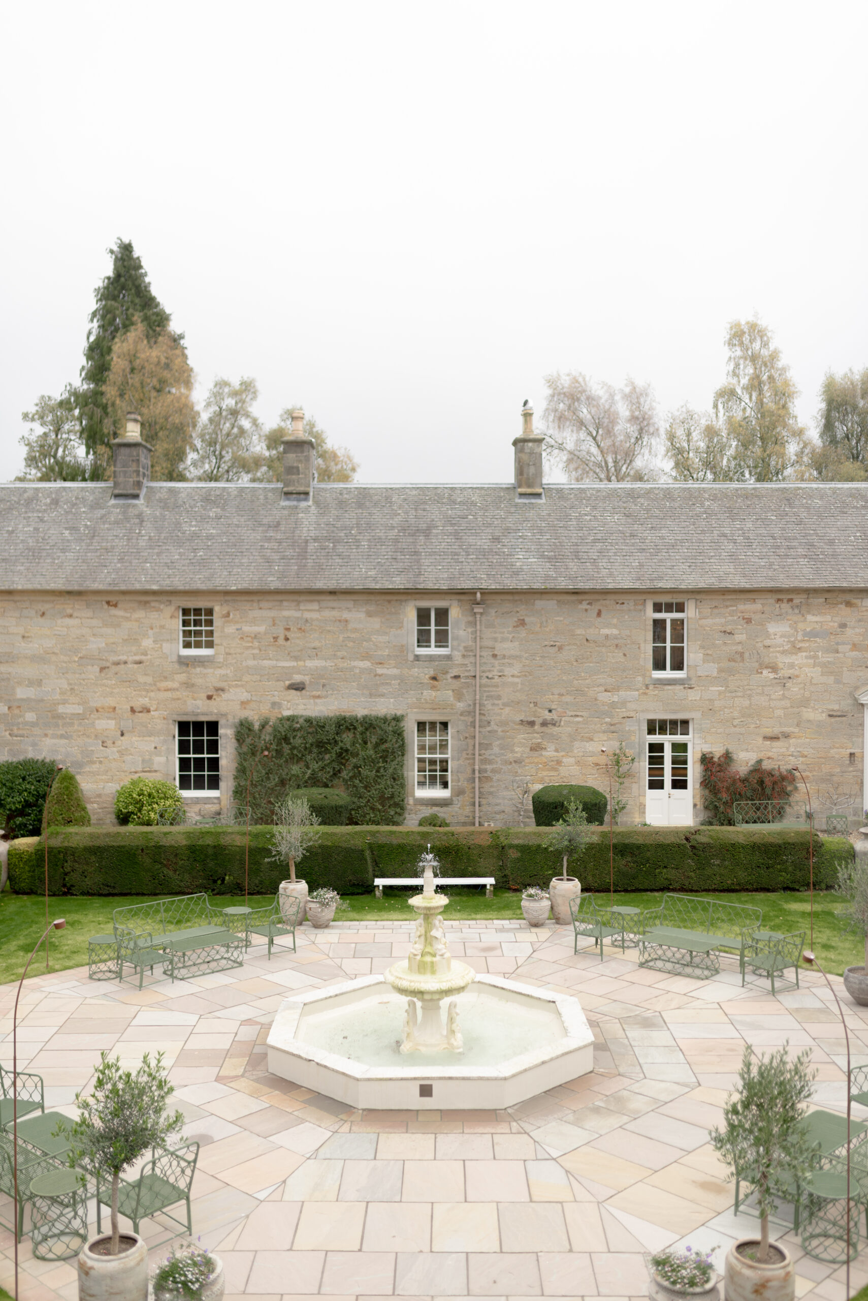 Penicuik Estate courtyard with elegant fountain, evergreen gardens and the storied, historic backdrop of the restored Penicuik House, near Edinburgh Scotland. Image by award winning fine art wedding photographer, Jill Cherry Porter. Top UK Wedding photographer featured in Vogue and Vanity Fair.