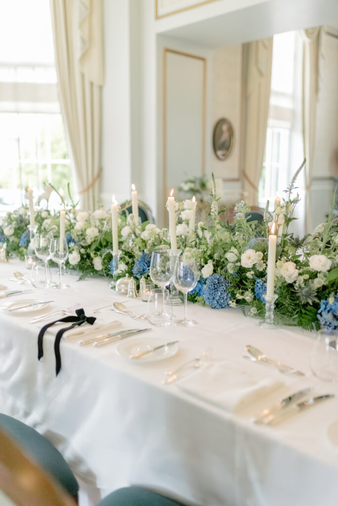 Gleneagles wedding room with blue, white and green hydrangea floral meadow, velvet bow place settings and taper candles, on a Gleneagles wedding day. Image by luxury fine art wedding photographer Scotland, Jill Cherry Porter.
