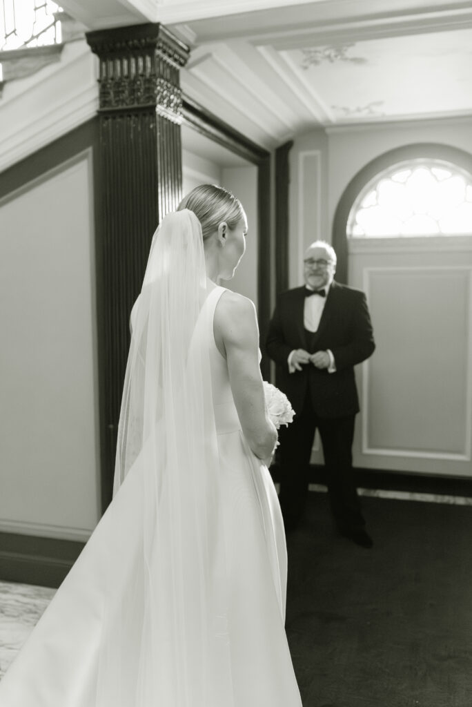 Black and white fine art wedding photography of a Bride and her Father as they approach the wedding ceremony on her Gleneagles wedding day. Image by luxury Gleneagles wedding photographer, Jill Cherry Porter.