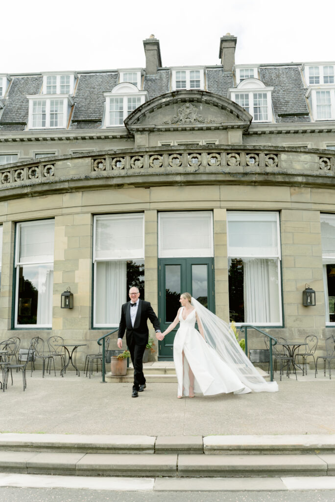 Bride and Groom on their Gleneagles wedding day, walking hand in hand in the grounds of the Gleneagles Hotel, Scotland. Image by award winning fine art wedding photographer, Jill Cherry Porter.
