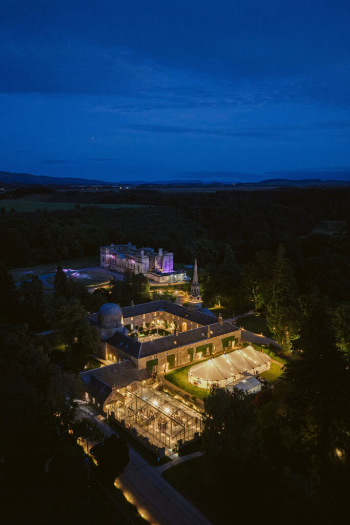 Penicuik Estate from above at twilight. The glow of a sailcloth marquee and Penicuik Estate's Glasshouse lit up on a wedding evening. Image by Penicuik Estate wedding photographer, Jill Cherry Porter.