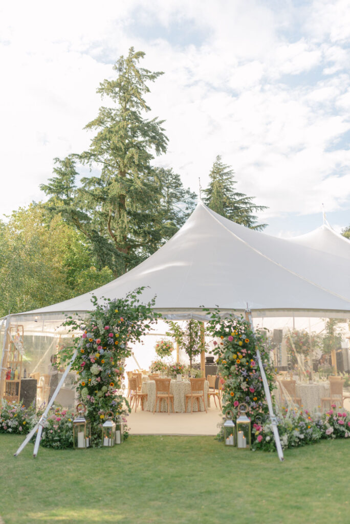 Scotland destination wedding design at Penicuik Estate. A sailcloth marquee entrance with wild florals, by Wild Flowers Edinburgh. Planned by wedding planner Coleen McKay. Image by Scotland Destination Wedding Photographer Jill Cherry Porter.