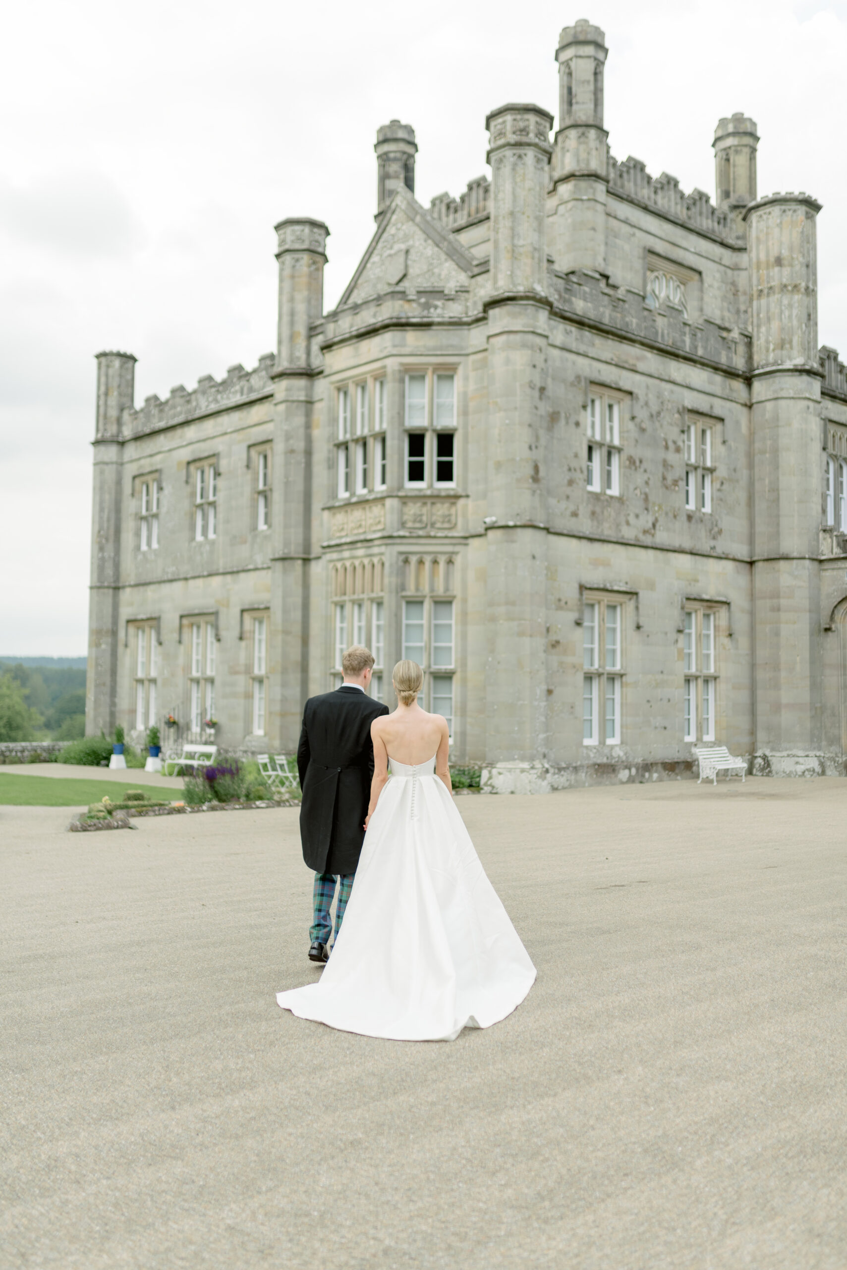 Bride and Groom walk hand in hand outside Blairquhan Castle Scotland, on their wedding day. Image by award-winning destination wedding photographer, Jill Cherry Porter.