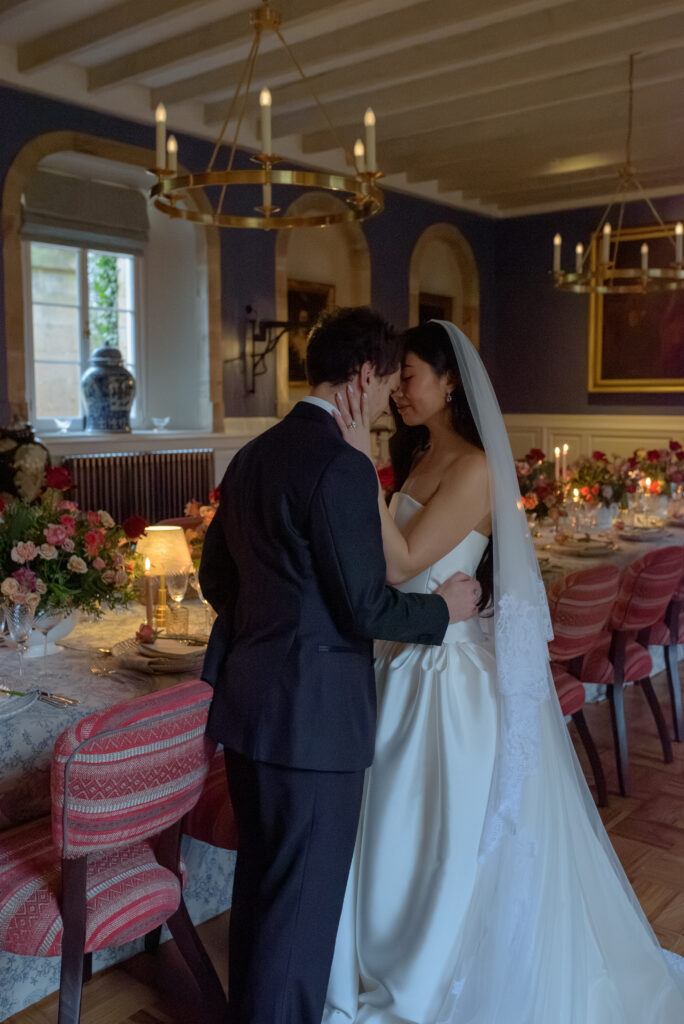 Bride and groom standing together inside Penicuik House reception room with floral installation and candlelight