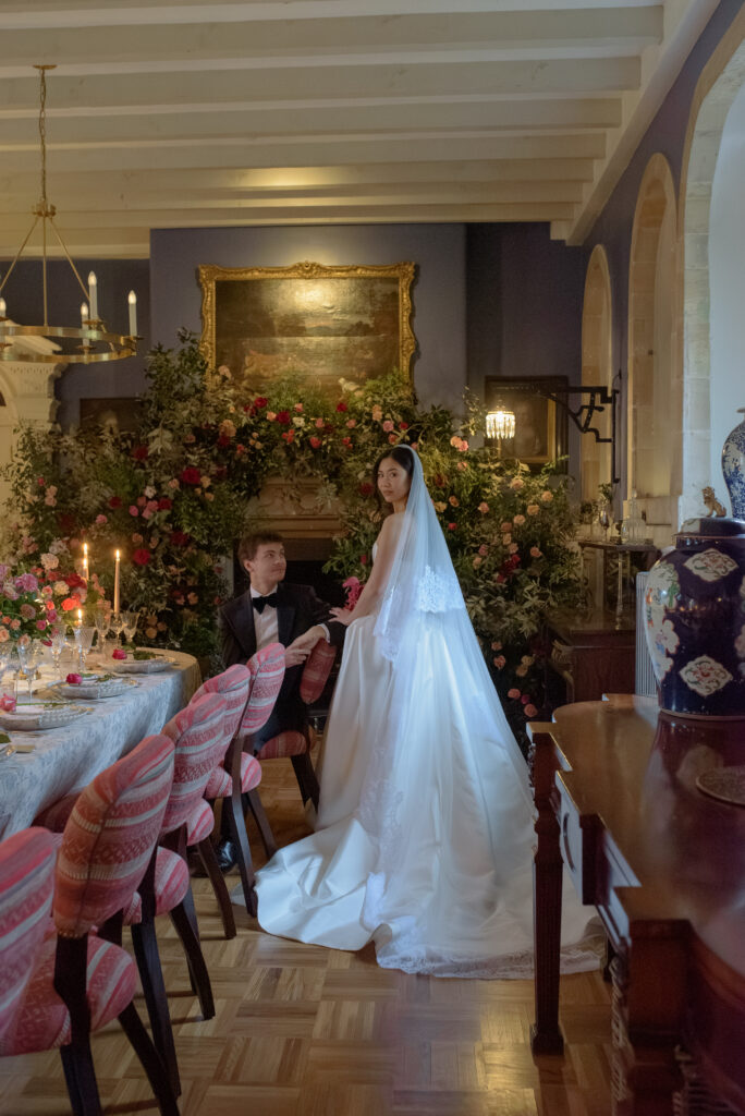 Bridal portrait of Bride and Groom by fireplace with flower installation in Penicuik House, Scotland. Wedding Photography by Jill Cherry Porter.