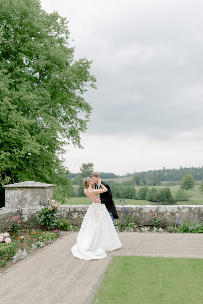 Bride and Groom embracing outdoors at a Scottish country private castle estate wedding with garden terrace and countryside views