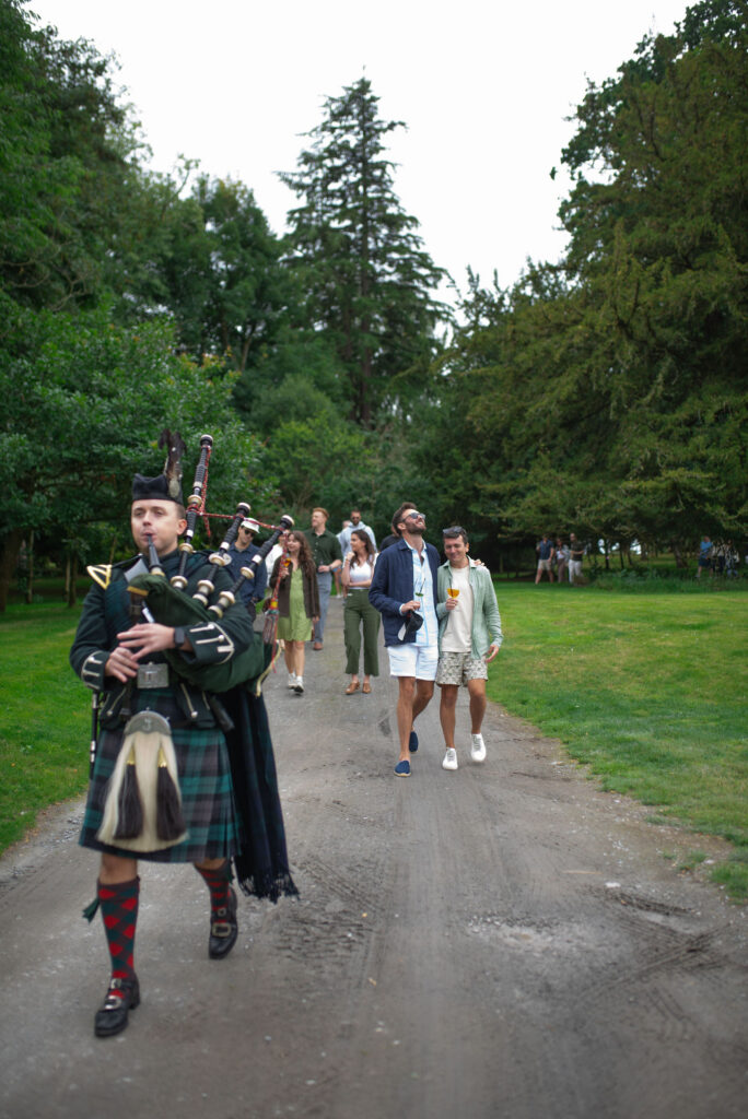 Piper pipes couple and guests to Highland Games wedding event on Penicuik Estate, Scotland destination wedding venue. Image by Penicuik House recommended wedding photographer, Jill Cherry Porter.