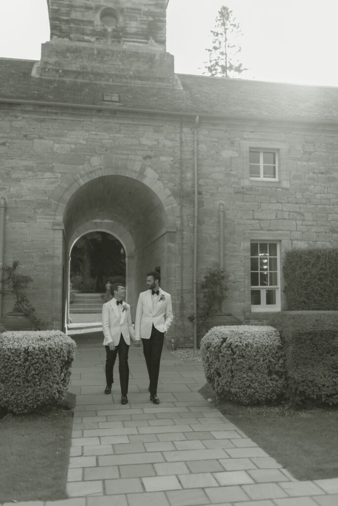 Grooms wander through the courtyard of Penicuik House, Scotland destination wedding venue on their wedding day. Image by Penicuik Estate recommended wedding photographer, Jill Cherry Porter.
